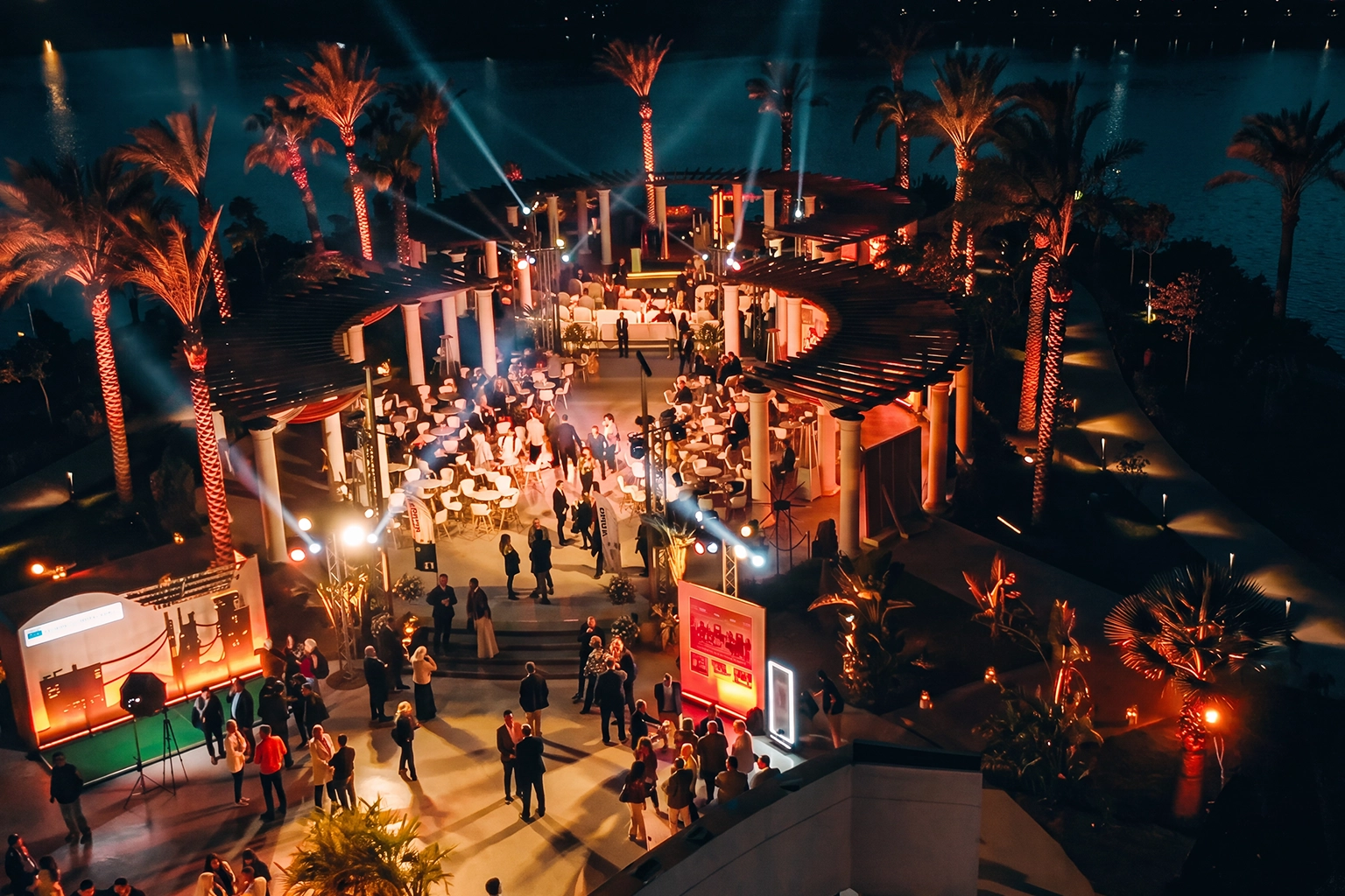 Aerial night view of an outdoor corporate gala in Cairo with stage lighting, beam effects, and hospitality zones, showing full production scale