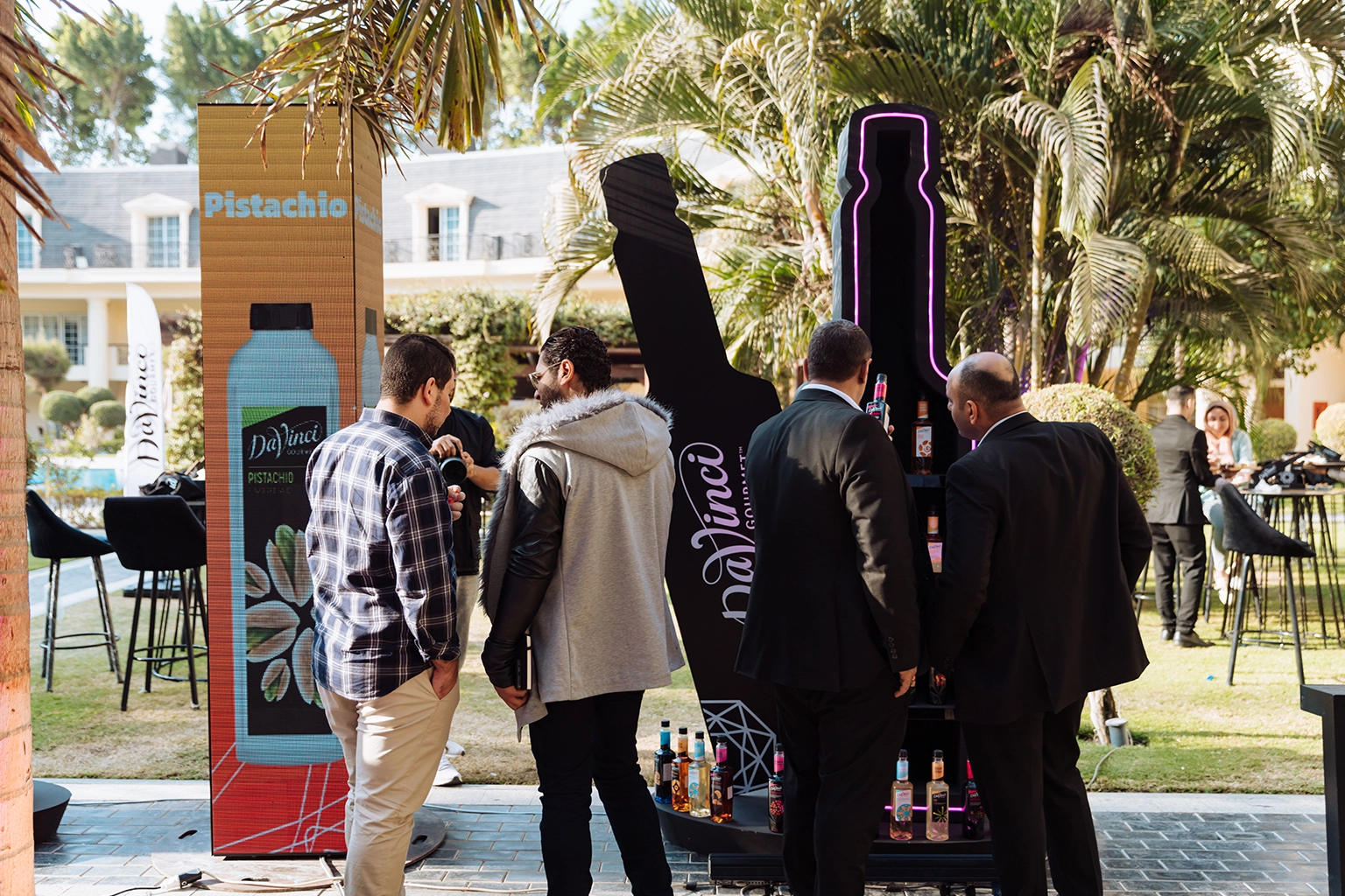 Visitors gathered around a bottle-shaped product display with LED screens at an outdoor brand activation in Cairo